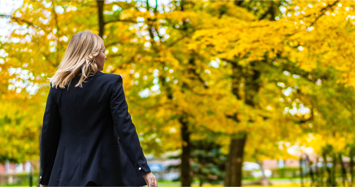 秋のファッションで公園を散歩する女性